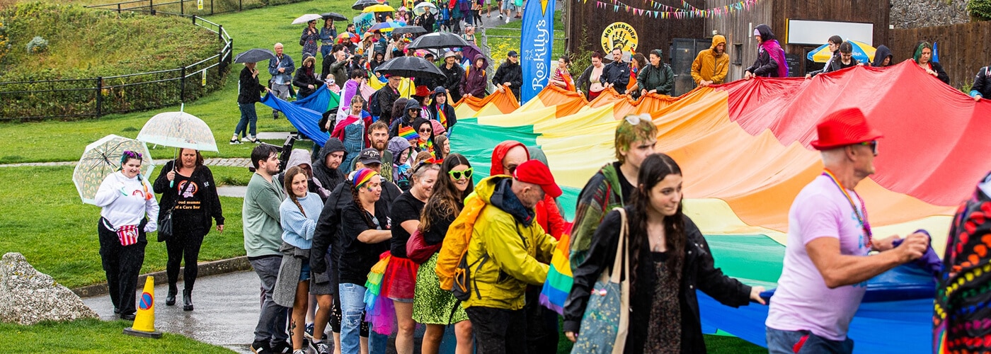 People carrying a rainbow flag through newquay for Cornwall Pride.