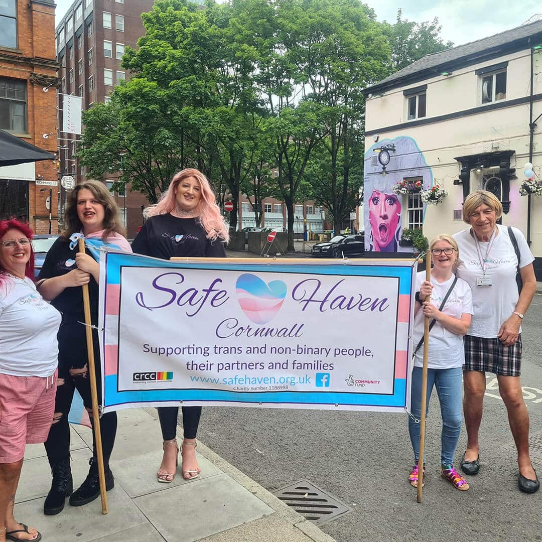 People holding a banner supporting trans and non-binary people in cornwall